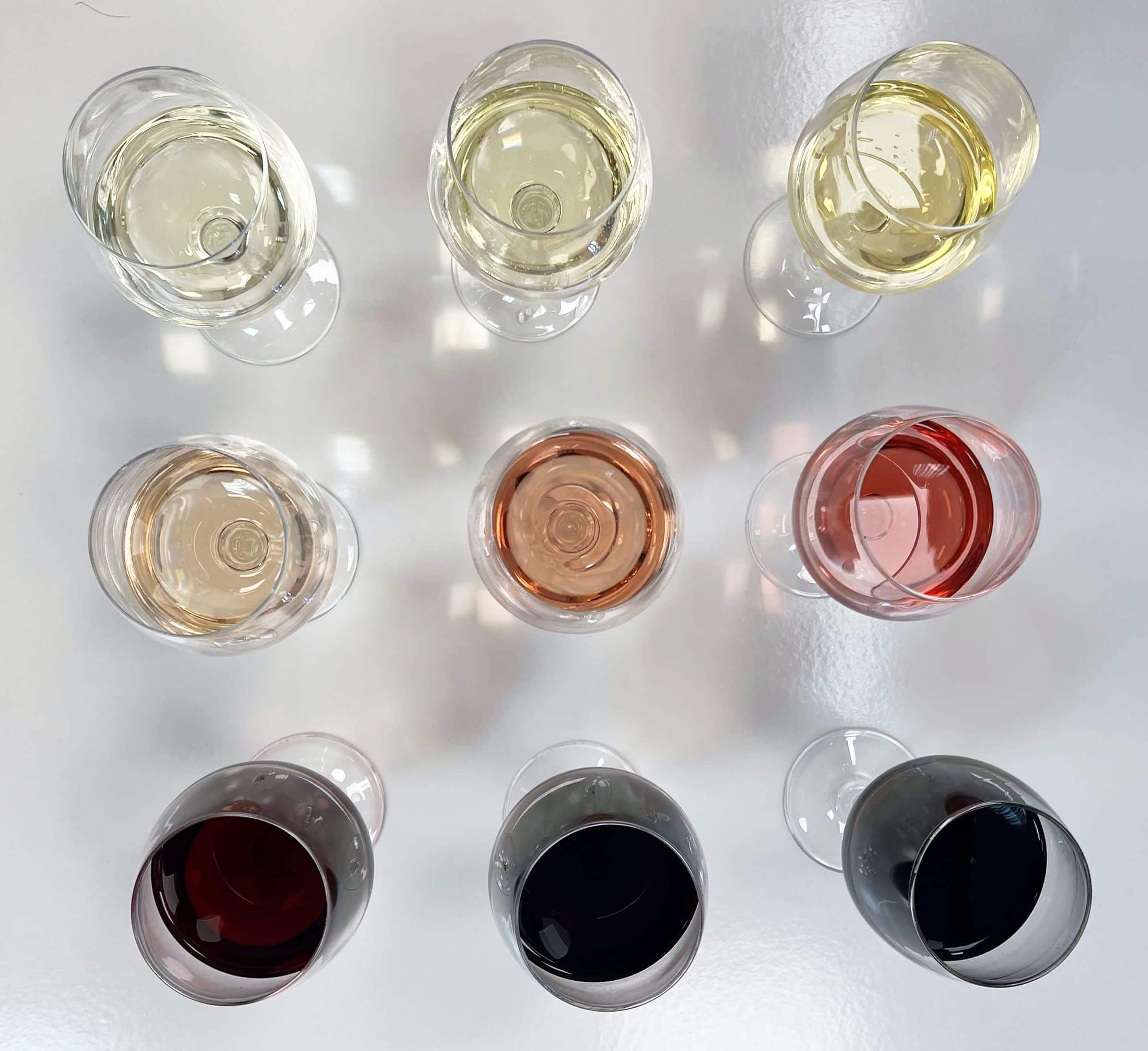 Ocho copas de vino de diferentes colores, mostrando la diversidad de vinos, incluyendo blancos, rosados y tintos.